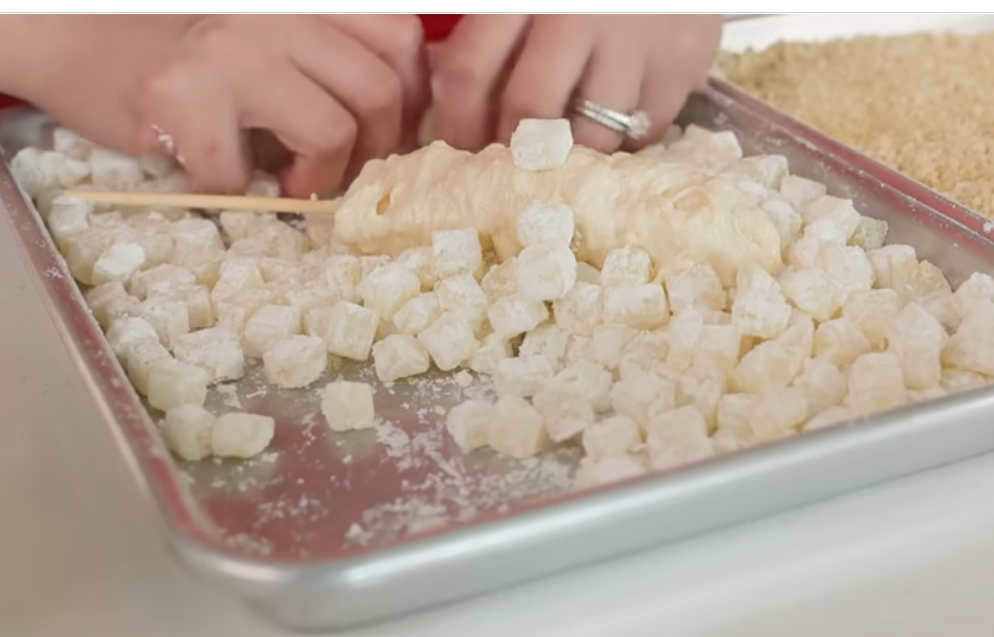 Assembling Korean corn dog with mozzarella cheese on a wooden stick
